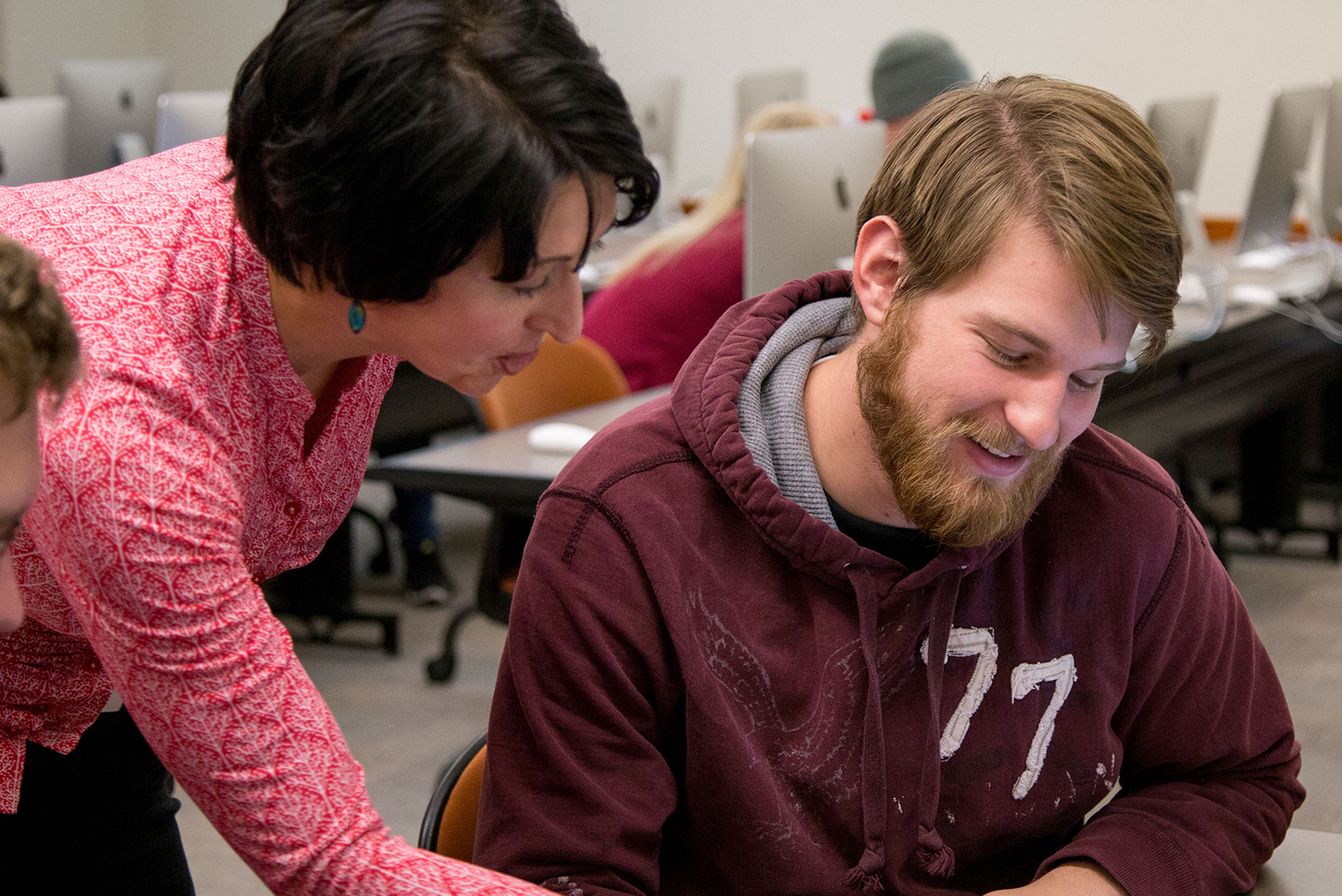 Professor helping students in a computer classroom setting