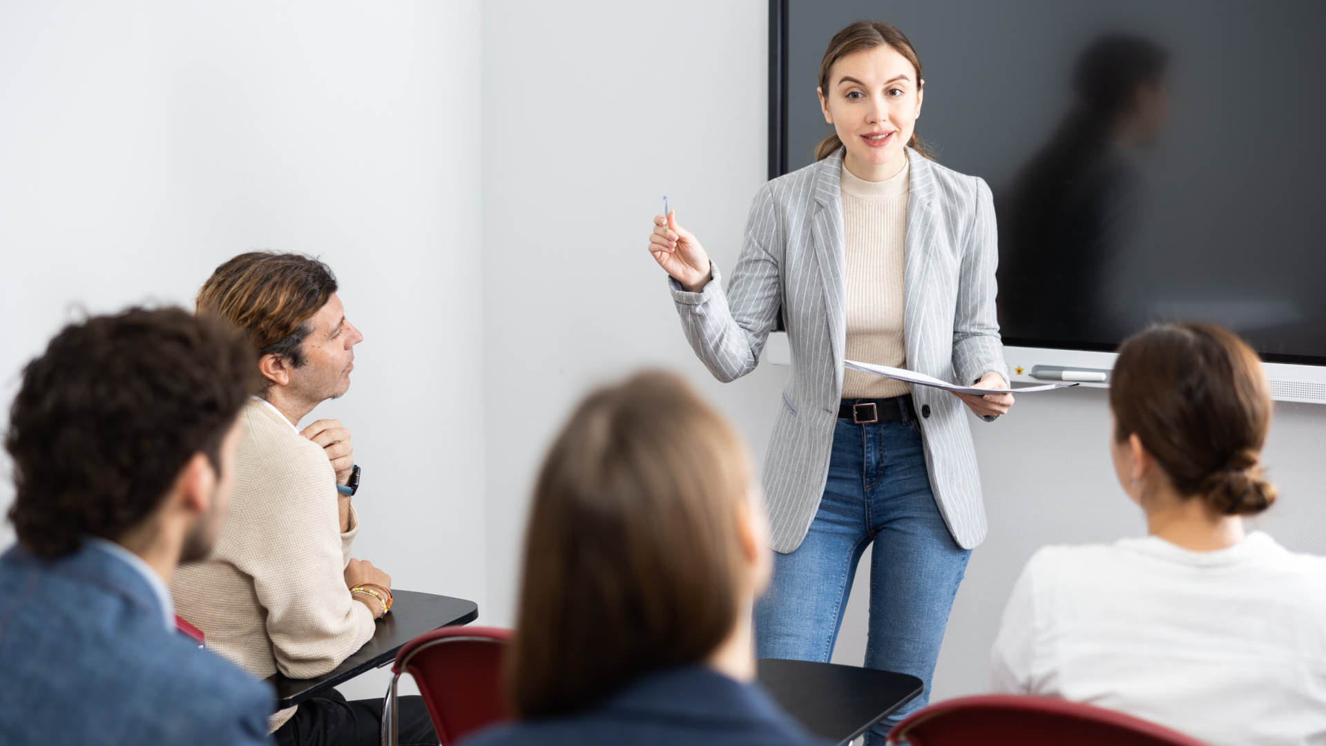Businesswoman presenting to seated colleagues in modern conference room