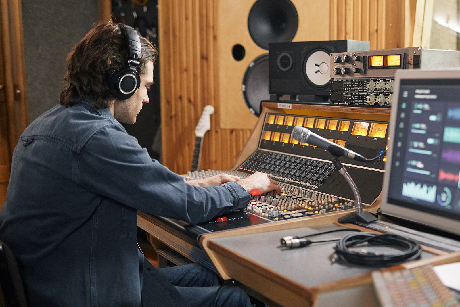 music technology student wearing headphones while using a mixing board